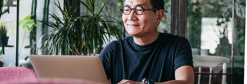 Smiling Chinese man working on laptop