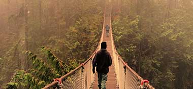 Two people walking across a rope bridge